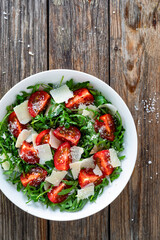 Naklejka na ściany i meble Arugula salad with tomatoes and parmesan cheese on wooden table 