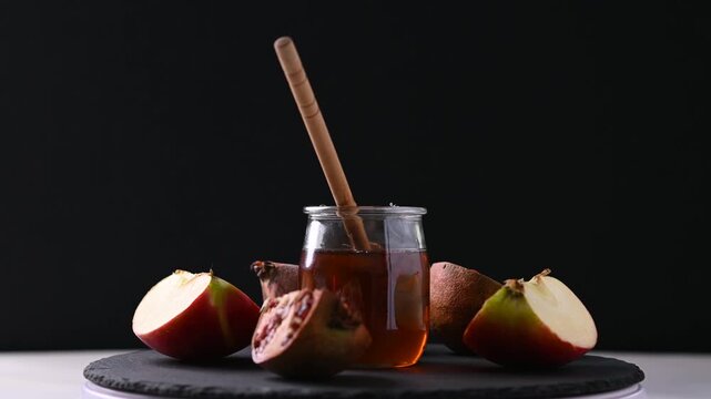 Rotating honey jar, pomegranates and apples for Rosh Hashanah celebration
