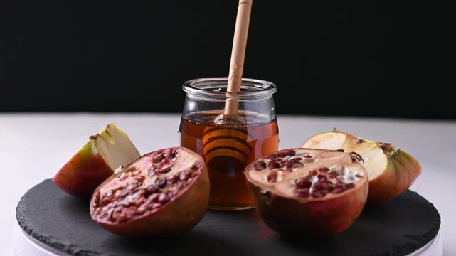 Rotating honey jar, pomegranates and apples for Rosh Hashanah celebration