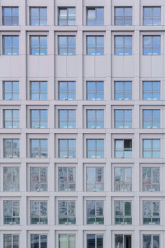 Window rows pattern on a flat bright facade of a contemporary high rise building. Minimalist architectural geometric grid texture of a modern urban house.