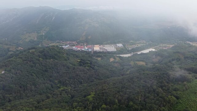 Aerial view through clouds of industrial zone and mountain landscape of Asturias, Spain