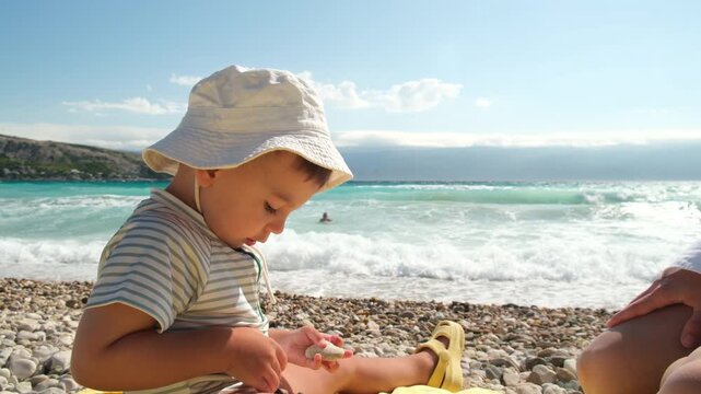 Toddler playing on a sunny pebble beach