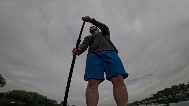 Man paddling SUP on cloudy lake