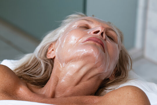 A tranquil woman lies peacefully with a facial mask, symbolizing self-care and rejuvenation through beauty rituals in a serene, relaxing spa atmosphere.
