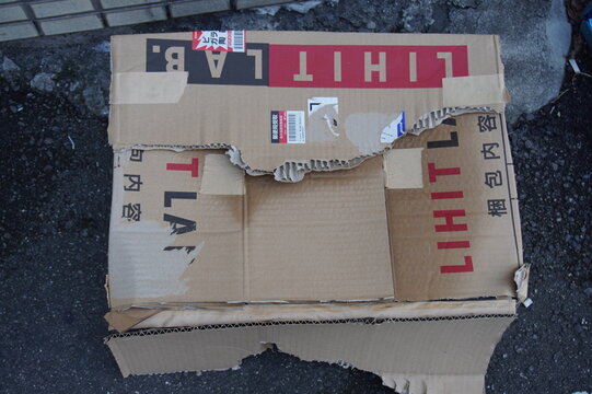 Damaged and torn cardboard delivery box placed on the ground in Japan