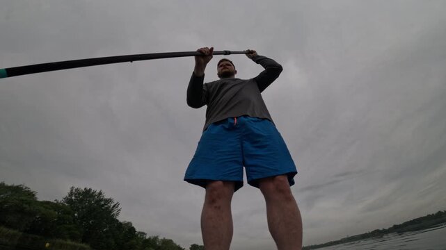 Man paddling SUP on cloudy lake