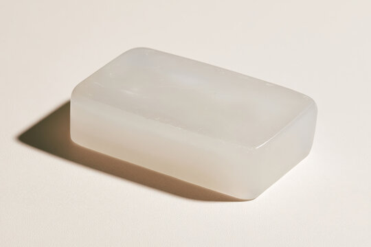 This sleek white soap bar beautifully contrasts with the minimalist background, showcasing its smooth surface and inviting texture, perfect for personal care branding.