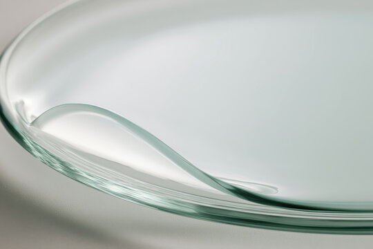 A close-up captures the curved edge of a glass dish holding a clear gel-like substance, inviting curiosity about its texture and potential applications in beauty or science.