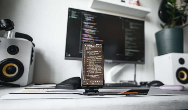 Minimal coding station featuring professional monitor with source code, organized accessories, speakers and fresh coffee. Bright home office supports software engineering, productivity and creative pr