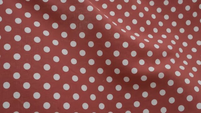 Seamless loop of vintage red fabric with white polka dots gently swaying in a light breeze creating soft fabric folds