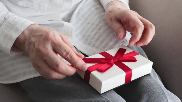 赤いリボンのプレゼントを受け取る高齢女性の手元／スローモーション／敬老の日