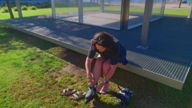 A Woman Prepares to Experience Outdoor Freedom by Strapping on Her Rollerblades at a Sunny Park, Enjoying the Thrill of Skating Among Nature's Beauty
