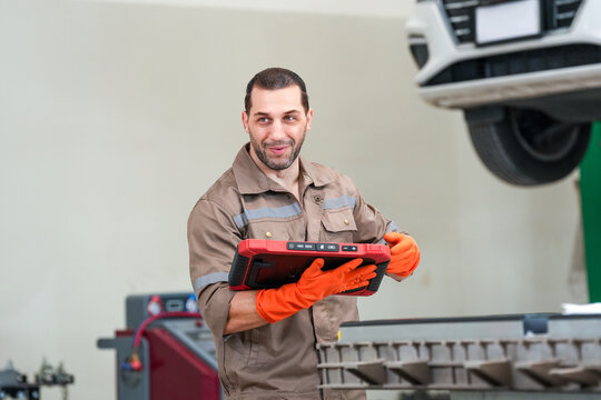 Mechanic car tablet garage glove repair vehicle service worker holding diagnostic tablet near lifted car in workshop