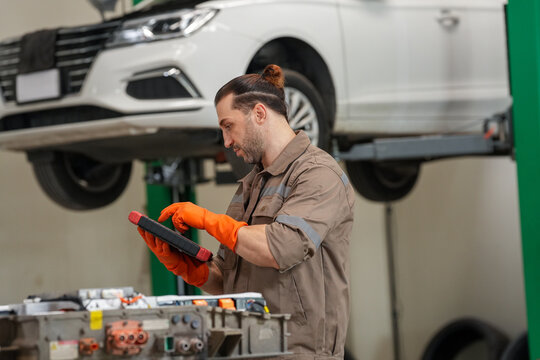 Car mechanic auto repair garage tablet glove vehicle, mechanic using tablet near lifted white car in repair garage