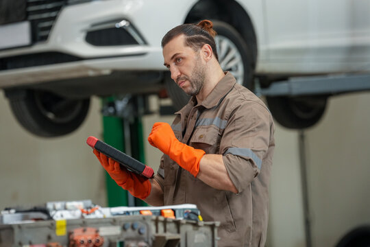 Car mechanic tablet glove repair garage vehicle inspection technician workshop male uniform tool lift service maintenance orange gray handheld