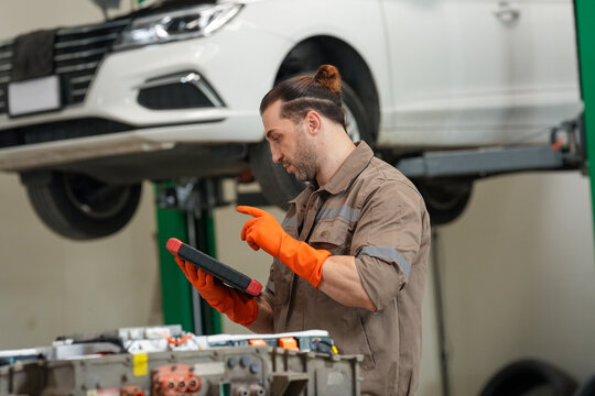 Car mechanic garage repair vehicle tablet glove workshop maintenance lift male mechanic garage repair vehicle with tablet and orange glove near