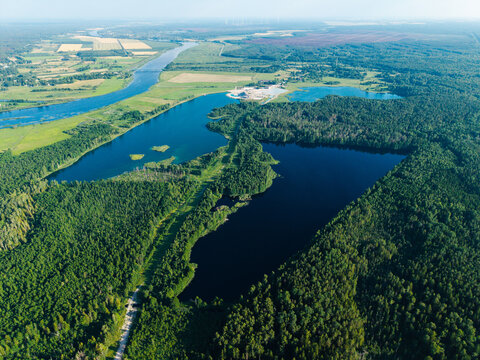 Aerial view of Kalnciems Dolomite Quarry surrounded by dense forests, peat extraction sites in Kaigu Bog, and wind turbines, Valgunde Parish, Jelgava Municipality, Latvia.