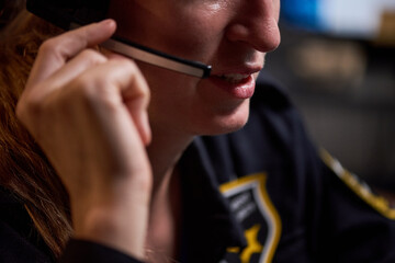 Close up of young adult Caucasian woman speaking through headset, handling customer support or emergency dispatch communication. Ideal for service center, help desk, response team marketing
