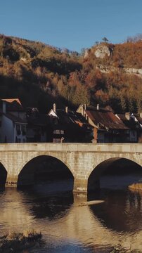 Panning shot of Saint Ursanne medieval town with Doubs river in autumn, Jura, Switzerland
