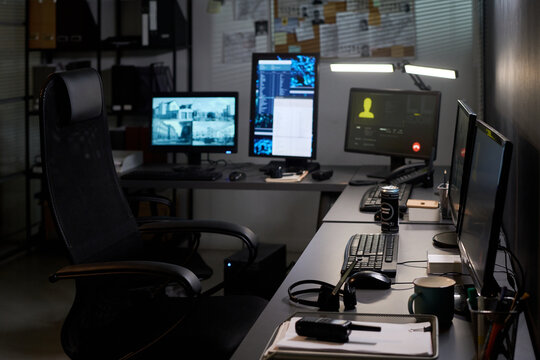 Wide shot of empty security office showing surveillance monitors, communication screen, headset, radio, supporting cybersecurity, monitoring, control room, workplace concepts