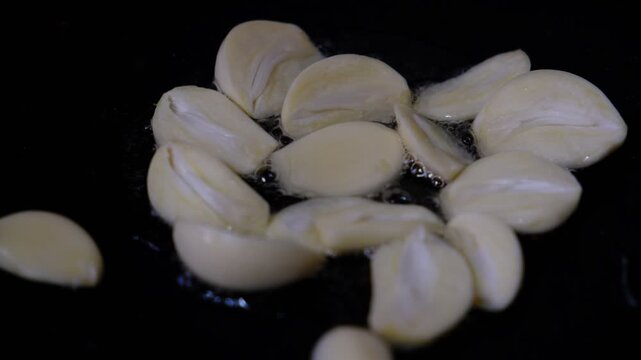 Chopped garlic frying in olive oil on a pan, close up. Сast iron skillet, Food in motion, process . Cooking, restaurant cookery