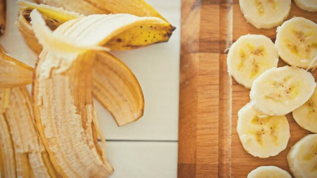 On a bright wooden table, a banana peel rests beside sliced banana rounds arranged on a cutting board, highlighting a fresh fruit snack that promotes nutrition, health and balanced eating habits