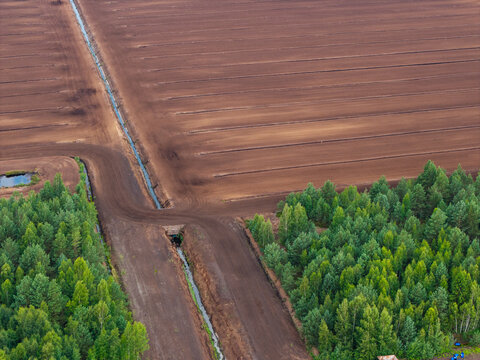 Aerial view of peat extraction fields with drainage ditches and surrounding forest in the Kaigu Bog Nature Reserve in Kaigu ciems, Jelgavas novads, Latvia.