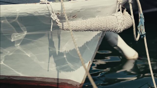 Close view of the bow of a traditional wooden boat with a rope fender moored above calm water in Zadar Croatia.