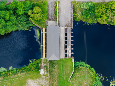 Aerial view of the bridge over the Vecberze river near its confluence with the Lielupe river, surrounded by lush green banks and trees in Kaigu ciems, Jelgavas novads, Latvia.