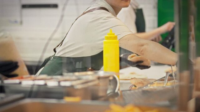 A chef in an apron and gloves cuts a fresh pita and fills it with juicy meat and vegetables. A concept for preparing popular street food for takeout at a fast food establishment