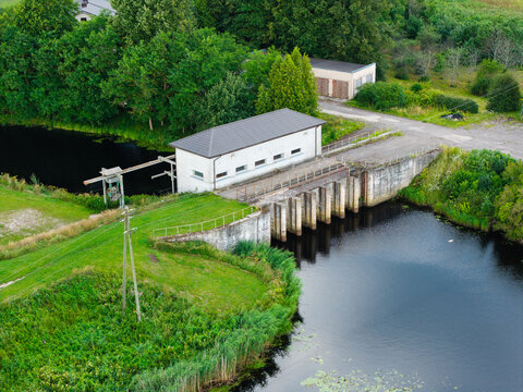Aerial view of the small dam structure on the Vecberze river near its confluence with the Lielupe river, surrounded by lush greenery and trees in Kaigu ciems, Jelgavas novads, Latvia.