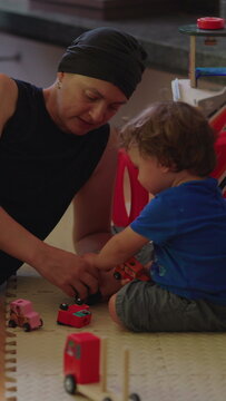 Mother and young child roll toy cars across the floor together at home, developing imagination, cooperation, communication and a joyful parent child relationship