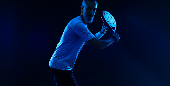 Padel tennis player with racket. Man athlete with paddle racket on court with neon colors. Sport concept.