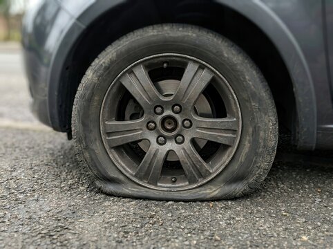 Deflated Car Tire Resting on Rough Asphalt Pavement