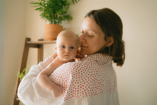 Mother embracing baby at home, creating a bond of care and warmth, showing the tender love and connection between parent and newborn during maternity