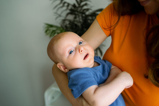 Mother holding her infant baby boy in her arms, showing bonding, love, and care between parent and child, highlighting the joy of new parenthood and family life