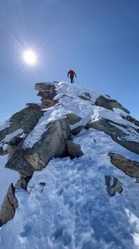 Hiker ascending top of Hochalmspitze summit in the Hohe Tauern Alps in winter, Carinthia, Austria
