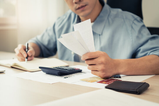 Deduction planning, debt asian accountant hand using calculator to calculating money balance from bill and income, cost budget expenses for pay money form personal individual on table at home.