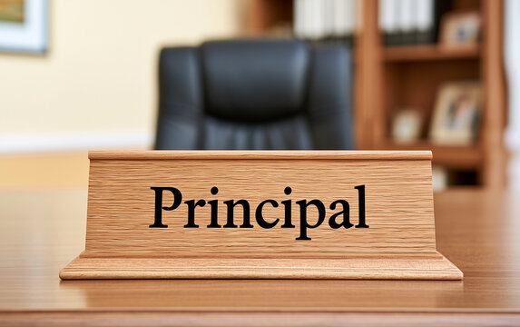 Principal office desk with nameplate. Black executive chair, wooden shelves, and files behind. Ready for school administration leadership meetings or educational policy discussions.