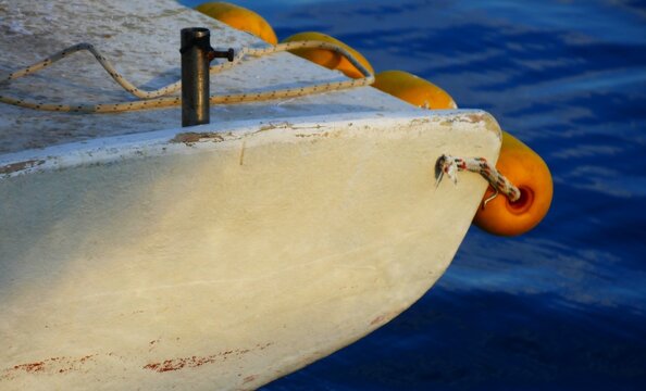 White fishing boat with yellow buoy and rope in harbor on the blue sea surface, sea nautical equipment