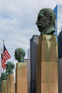 Chicago, Illinois, USA, October 2, 2024 - Vertical view of bronze busts atop tall pillars representing America's foremost merchants on the plaza in front of the Merchandise Mart