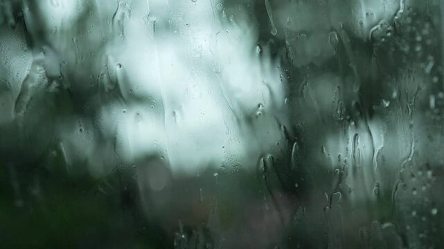 Close Up Rain Drops on Window with Blurred Green Trees