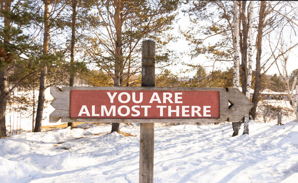 You are almost there words symbol. Concept words You are almost there on beautiful wooden road sign. Beautiful snow background. Business You are almost there motivational support concept. Copy space.