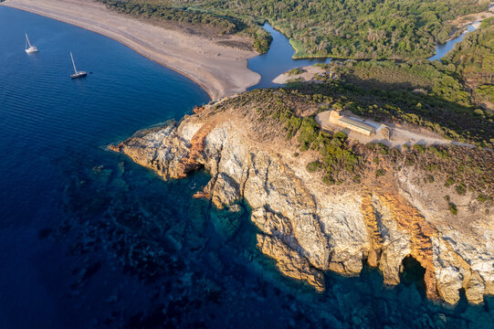 Aerial view of the historic Genoese tower of Galeria situated on a rocky headland overlooking the Mediterranean Sea, with the Fango river mouth and a sandy beach in Galeria, Corsica, France.