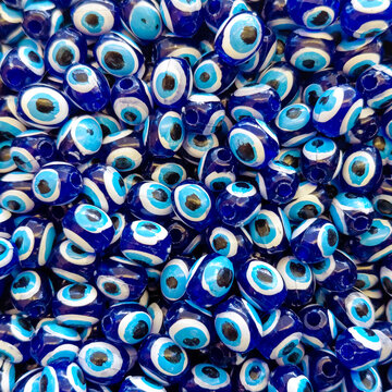 Blue Evil Eye Beads Background Pattern. Traditional Turkish Nazar Amulet Texture. Close-up view of traditional Turkish evil eye beads (nazar amulets) forming a dense blue pattern background.