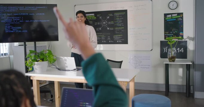 Indian teacher leading 3 female teens teaching using laptop in workshop nodding to raised hand