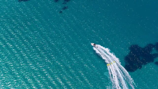 Golden Beach speedboat towing tubes with riders on turquoise sea