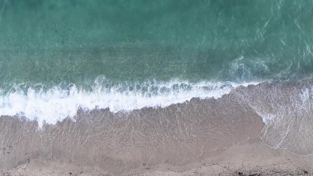 Turquoise sea along a sandy Greek beach with foamy white waves