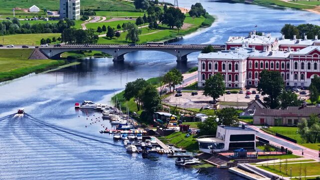 Jelgava, Latvia - 03 August 2025: Aerial view of Jelgava Palace situated along the Lielupe River with a bridge, boats docked at the marina, and surrounding green parklands.