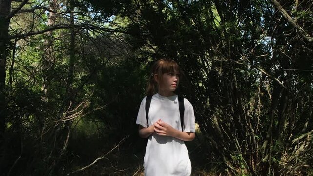 Worried lonely girl walking through a forest concerned that she is lost and realizes she lost her way. Danger of children in woodland without adults. Missing person search concept.